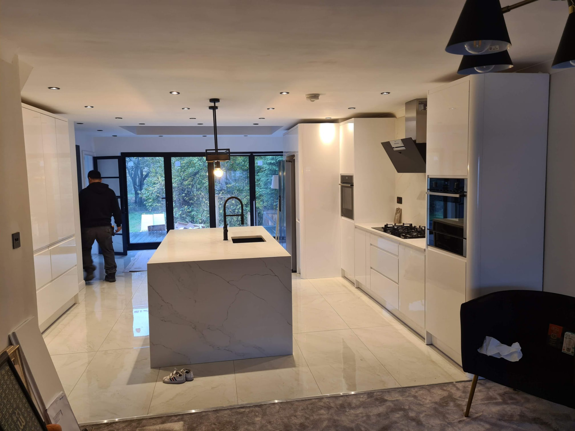 Finished modern white kitchen with large marble island and black bi-fold doors, Leeds