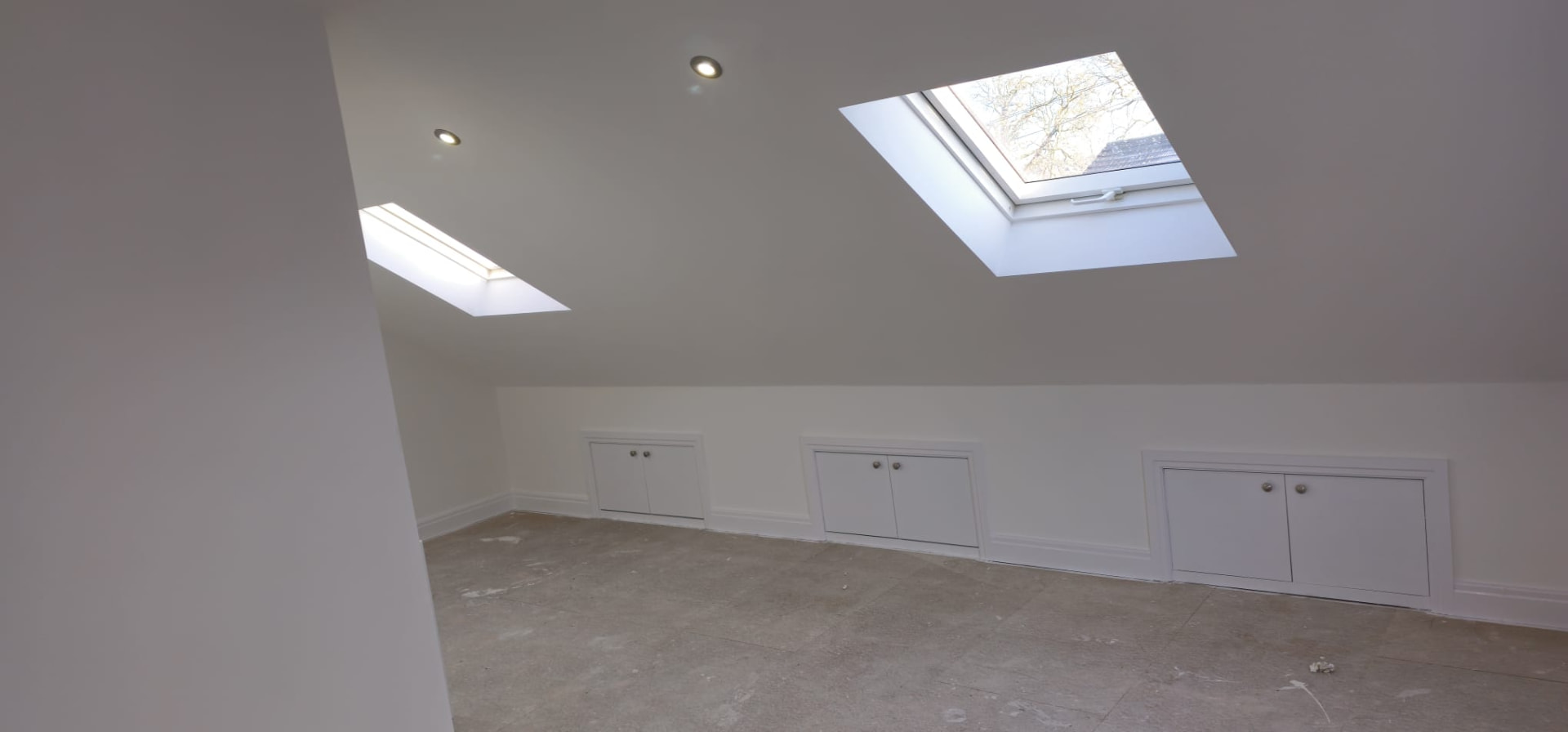 Completed loft conversion in Leeds with twin skylights, plastered pitched ceiling and built-in eaves storage