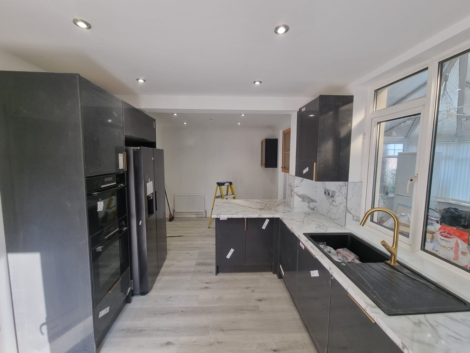 Completed dark grey handleless kitchen with marble worktops and brass tap, Leeds